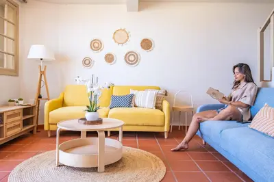 a woman sitting on a couch reading a book in a living room at Hilani House by Homie in São Vicente