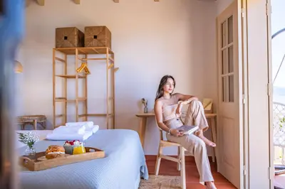 a woman sitting on a chair in a bedroom at Hilani House by Homie in São Vicente