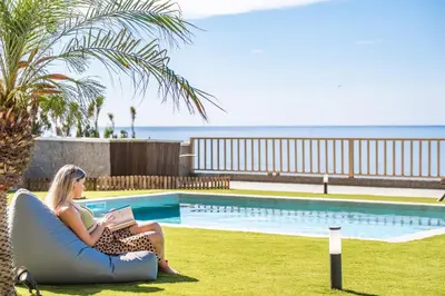 a woman sitting on an arm chair next to a pool at Hilani House by Homie in São Vicente