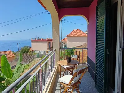 a balcony with a table and chairs and the ocean at Casa Central - Peceful Mountain Retreat in Calheta in Arco da Calheta