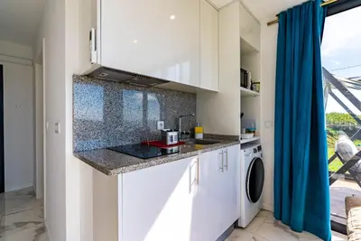 a kitchen with white cabinets and a washer and dryer at Casa Branca-A, beautiful sea view in Estreito da Calheta