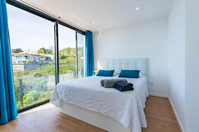 a bedroom with a white bed and a large window at Casa Branca-A, beautiful sea view in Estreito da Calheta