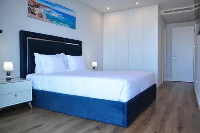 a bedroom with a large white bed and a blue wall at Enchanted Bay in Câmara de Lobos