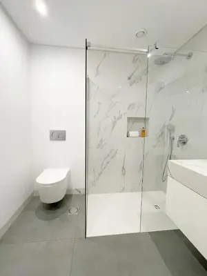 a bathroom with a glass shower and a toilet at Enchanted Bay in Câmara de Lobos