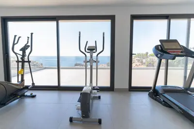 a gym with cardio machines and a view of the ocean at Enchanted Bay in Câmara de Lobos