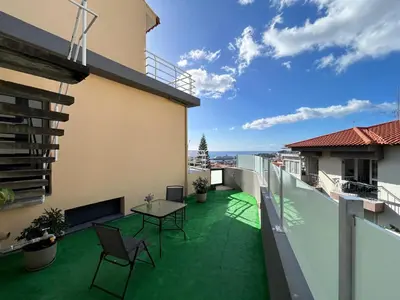 a balcony with green flooring and a table and chairs at Funchal Casa in Funchal
