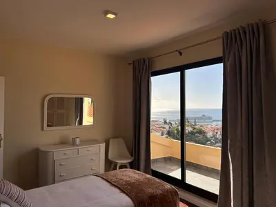 a bedroom with a large window with a view of the ocean at Funchal Casa 2 in Funchal