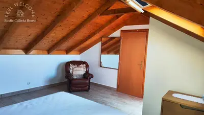 a bedroom with a chair and a wooden ceiling at Rustic Calheta House in Arco da Calheta