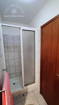 a bathroom with a shower and a glass door at Rustic Calheta House in Arco da Calheta