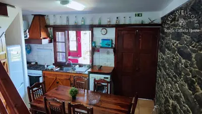 a kitchen with a wooden table and a dining room at Rustic Calheta House in Arco da Calheta