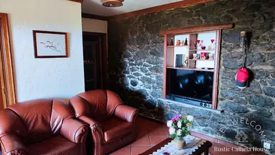 a living room with a leather couch and a television at Rustic Calheta House in Arco da Calheta