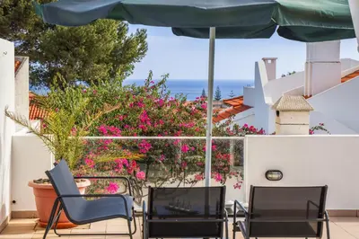 two chairs and an umbrella on a patio with flowers at Casa Bambi in Porto Santo