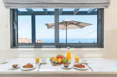a table with food and a window with an umbrella at Sapphire Sands by Atlantic Holiday in Estreito da Calheta