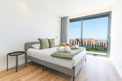 a white bedroom with a bed and a large window at Sapphire Sands by Atlantic Holiday in Estreito da Calheta