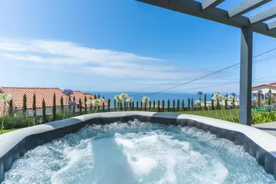 a hot tub on a patio with the ocean in the background at Sapphire Sands by Atlantic Holiday in Estreito da Calheta