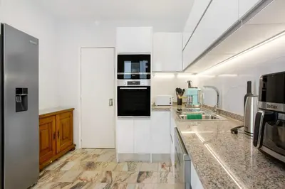 a kitchen with white cabinets and a black oven at Casa Caminho do Palheiro - Funchal in Funchal
