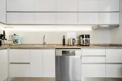 a kitchen with white cabinets and a stainless steel refrigerator at Casa Caminho do Palheiro - Funchal in Funchal