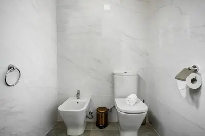 a white bathroom with a toilet and a sink at Casa Caminho do Palheiro - Funchal in Funchal