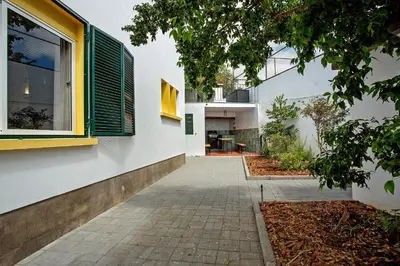 a house with a yellow window and a sidewalk at Casa Caminho do Palheiro - Funchal in Funchal
