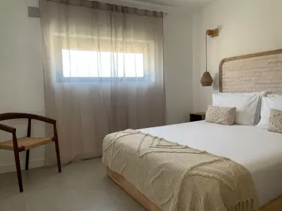 a bedroom with a bed and a chair and a window at Casa Amado in Carrapateira