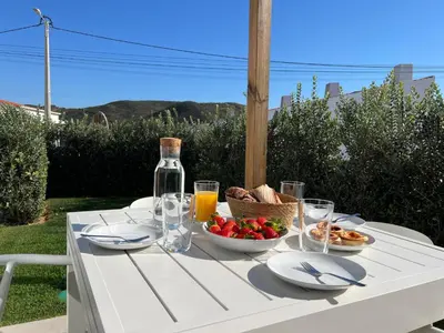 a white table with a bowl of food and a bottle of wine at Casa Amado in Carrapateira