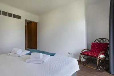 a bedroom with a white bed and a red chair at D13 - Eiras Velhas Holiday House in Almádena in Almádena