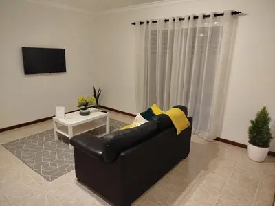 a living room with a black couch and a tv at MCR Calheta in Calheta