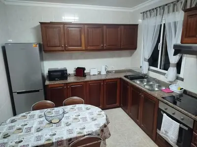 a kitchen with wooden cabinets and a table and a refrigerator at MCR Calheta in Calheta