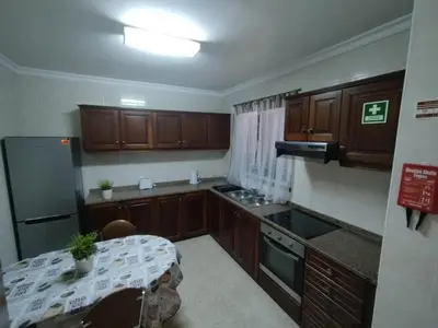 a kitchen with wooden cabinets and a table in it at MCR Calheta in Calheta