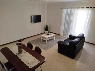a living room with a black leather couch and a table at MCR Calheta in Calheta