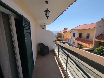 a balcony with a chair and a view of a building at MCR Calheta in Calheta