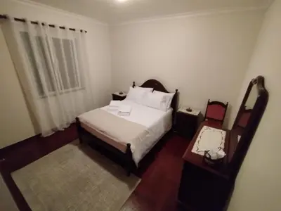 a bedroom with a white bed and a table and a window at MCR Calheta in Calheta