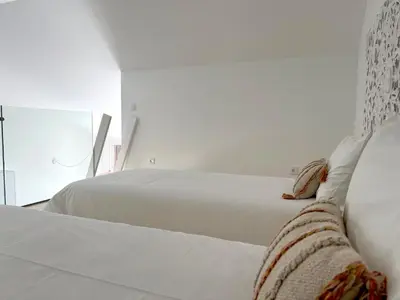 two white beds in a bedroom with white walls at Casa Amoreira in Carrapateira
