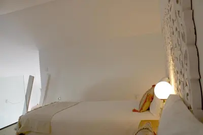 a bedroom with a white bed and a lamp at Casa Amoreira in Carrapateira