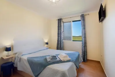 a bedroom with a bed with blue sheets and a window at Levada Residence in Funchal