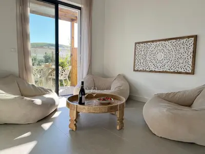 a living room with two chairs and a table with a bottle of wine at Casa Arrifana in Carrapateira