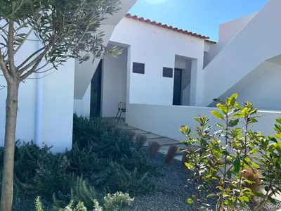 a house with white walls and a tree at Casa Arrifana in Carrapateira