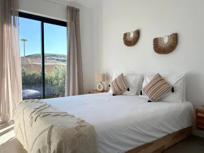 a bedroom with a white bed with a large window at Casa Castelejo in Bordeira