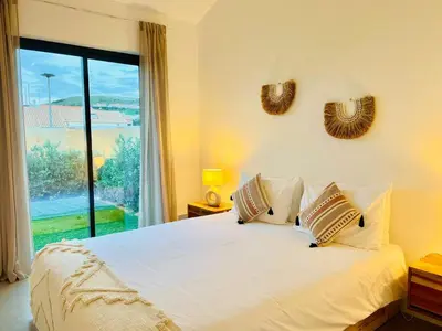 a bedroom with a white bed with a large window at Casa Castelejo in Bordeira