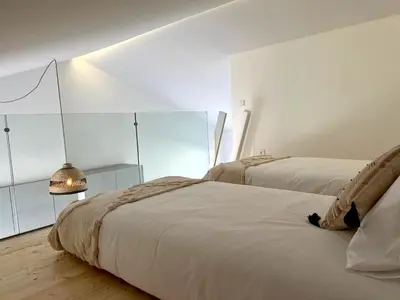 a white bedroom with two beds and a lamp at Casa Castelejo in Bordeira