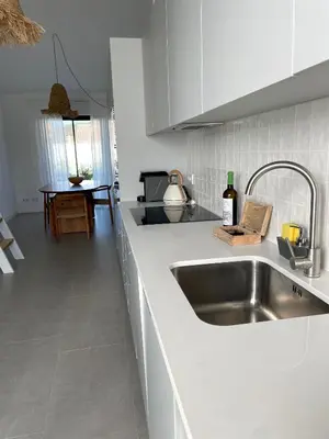 a kitchen with a stainless steel sink and white cabinets at Casa Cordoama in Bordeira