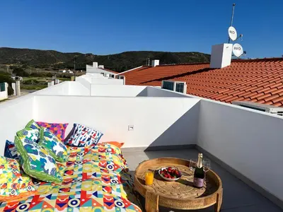 a patio with a couch and a table on a balcony at Casa Cordoama in Bordeira