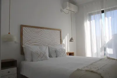 a white bedroom with a large bed with white pillows at Casa Cordoama in Bordeira