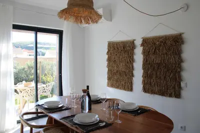 a dining room table with glasses and a bottle of wine at Casa Cordoama in Bordeira