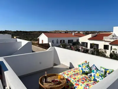a couch on a balcony with a view of the ocean at Casa Cordoama in Bordeira