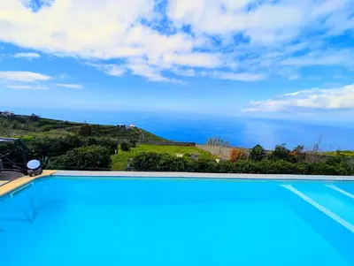 a bedroom with a bed and a desk and a window at Madeira Native Motion Guest House in Fajã da Ovelha