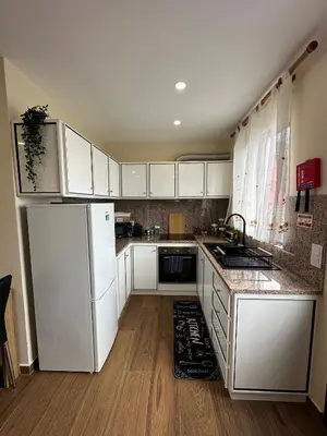 a kitchen with white cabinets and a white refrigerator at Vila Romana in São Vicente