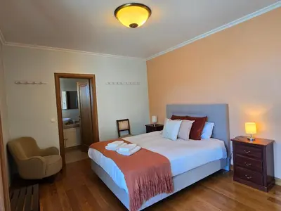 a bedroom with a bed with a chair and a lamp at Penthouse in the center of Funchal in Funchal