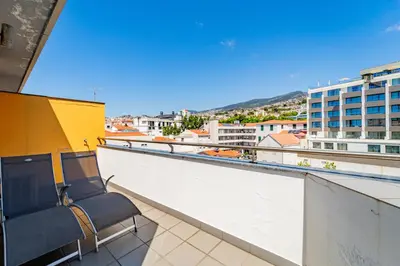 a balcony with two chairs and a view of a city at Penthouse in the center of Funchal in Funchal