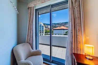 a room with a chair and a window with a view at Penthouse in the center of Funchal in Funchal
